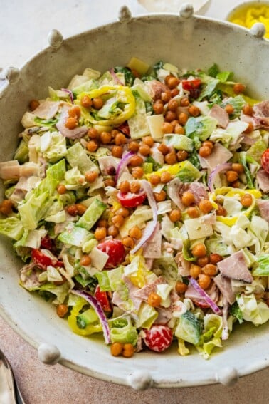 Grinder salad in a large serving bowl with chickpeas, veggies, and deli meats.