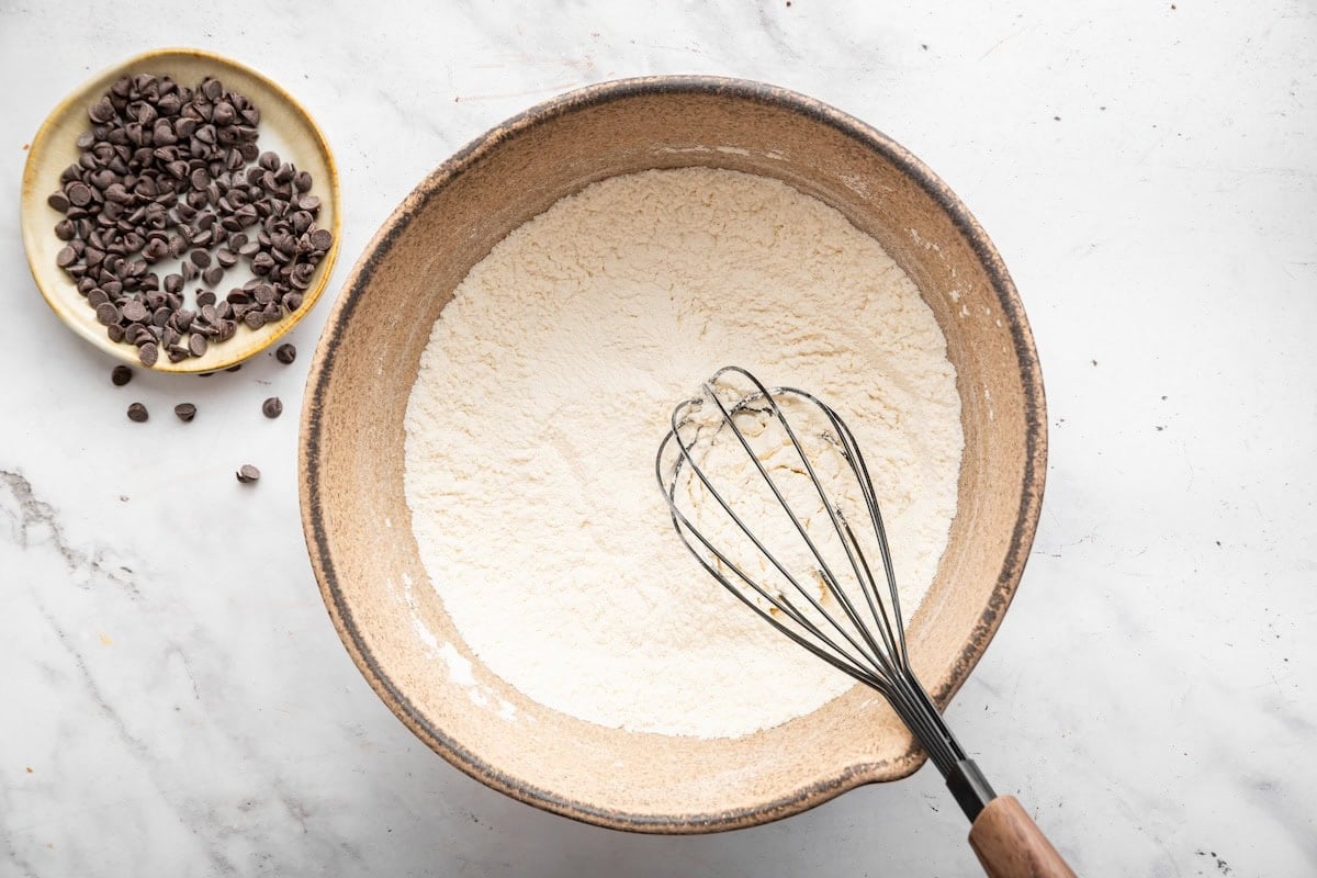 Dry ingredients with a whisk in a bowl used for chocolate chip muffins.