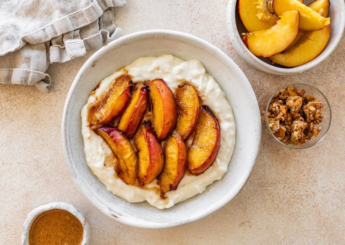 Peach slices topped in a bowl with greek yogurt and cottage cheese with protein powder.