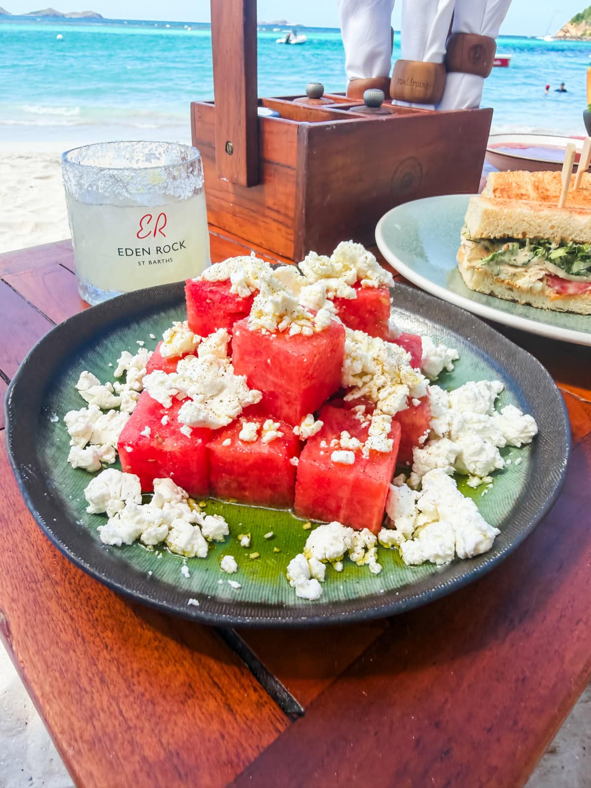 Watermelon feta salad with Eden Rock branded glass and club sandwich at the Sand Bar