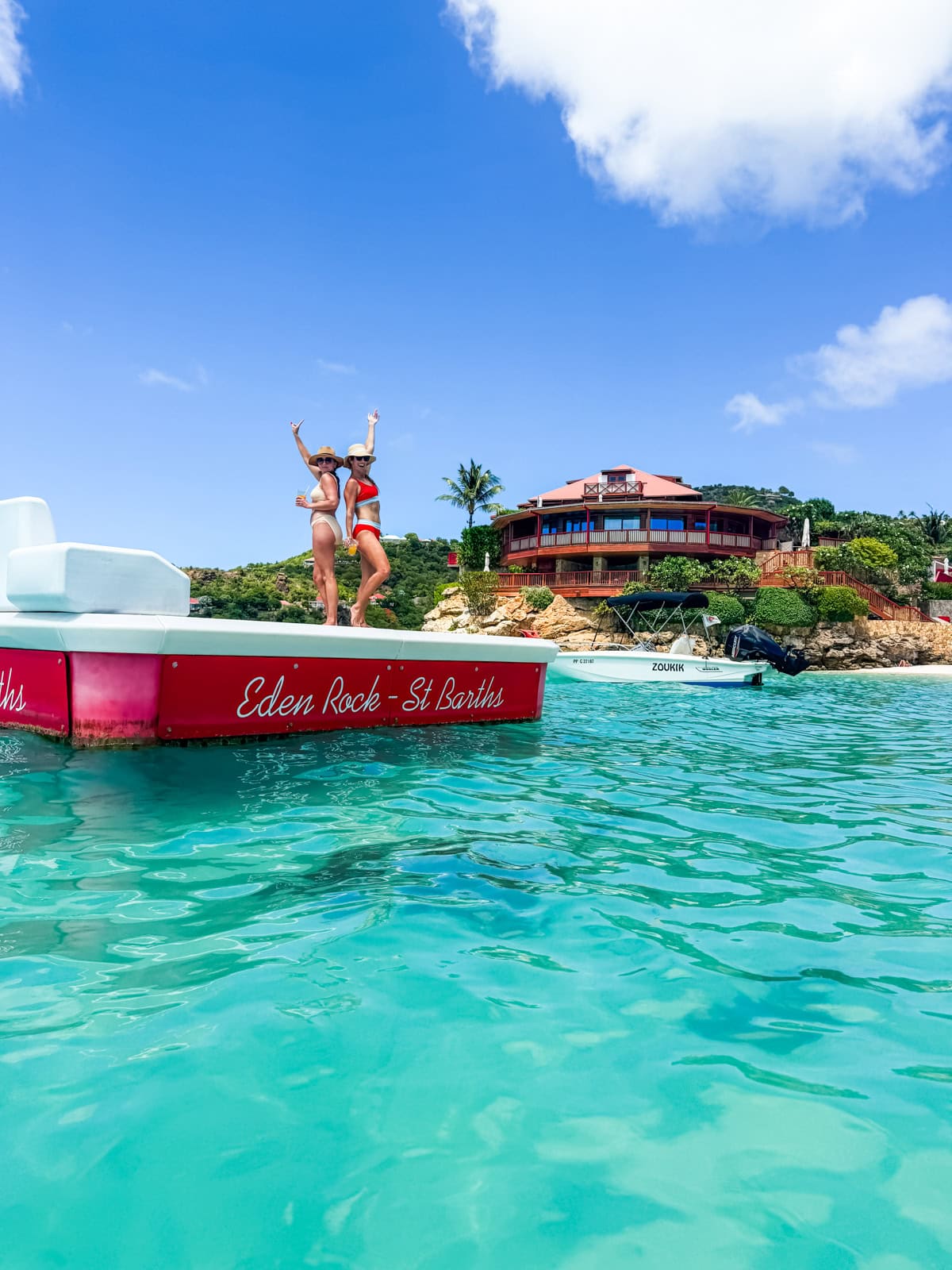 Brittany and friend standing on the Eden Rock boat with turquoise water and the hotel in the background