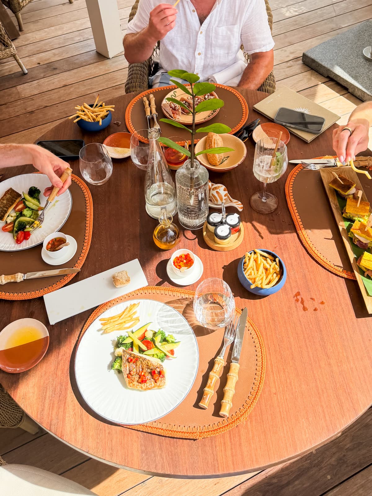 Aerial view of Cheval Blanc lunch table with fish, fries, and multiple dishes on the terrace