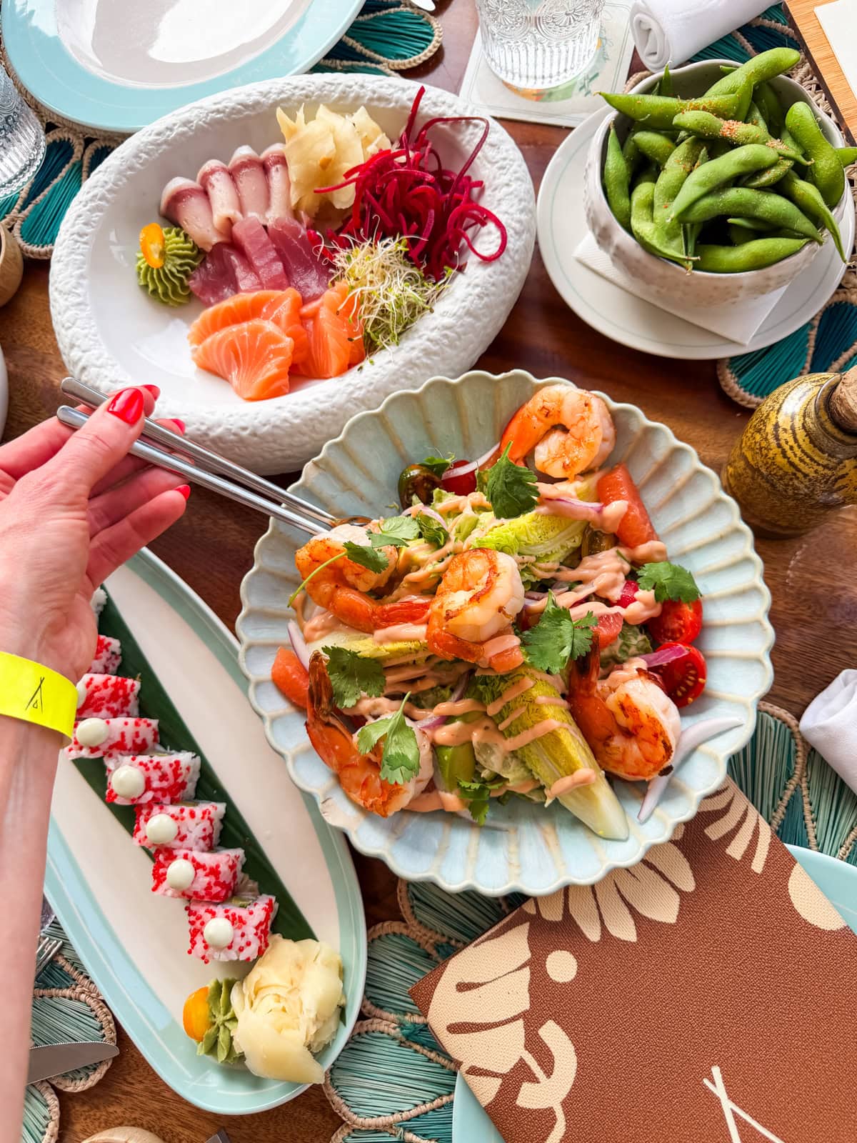 Nikki Beach food spread with sashimi, shrimp salad, and sushi rolls