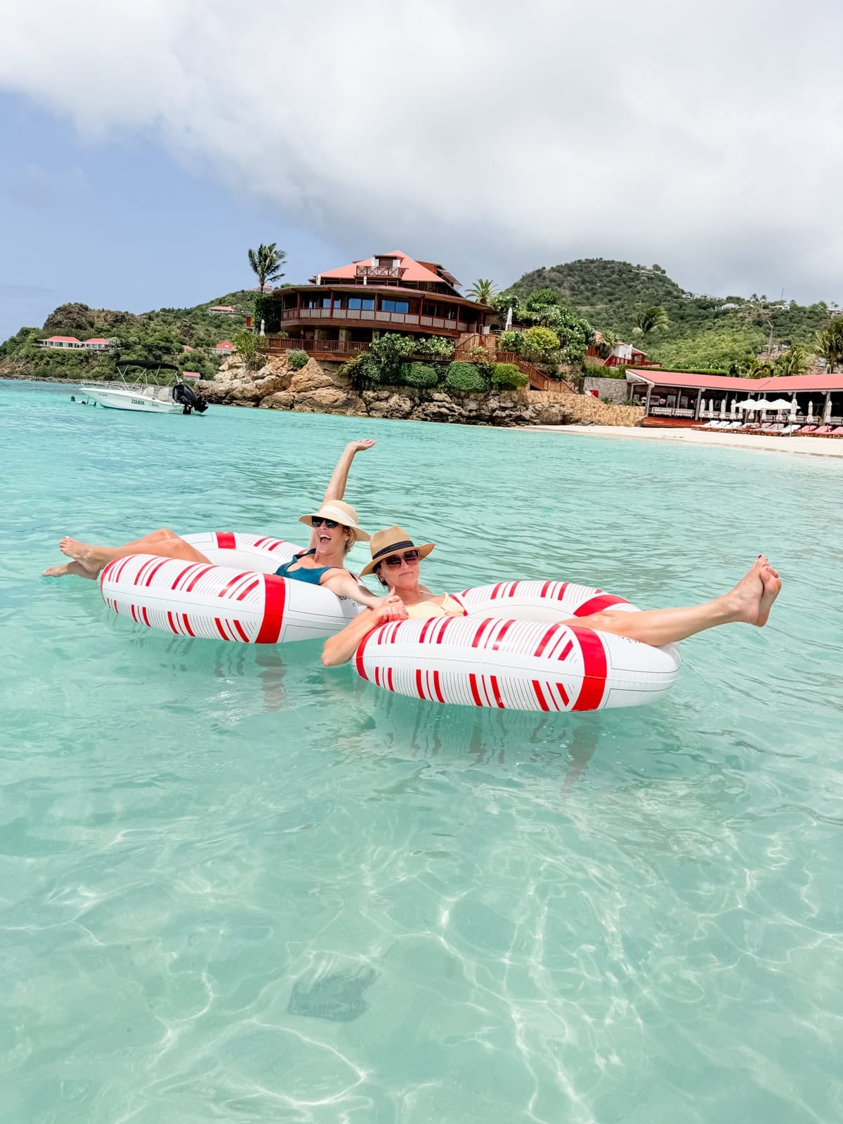 Two friends floating on inflatable rings in crystal clear water at St. Jean Beach, Eden Rock St. Barths