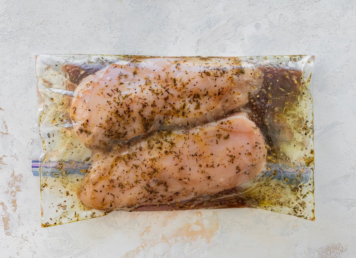 Raw chicken marinating in a plastic bag.