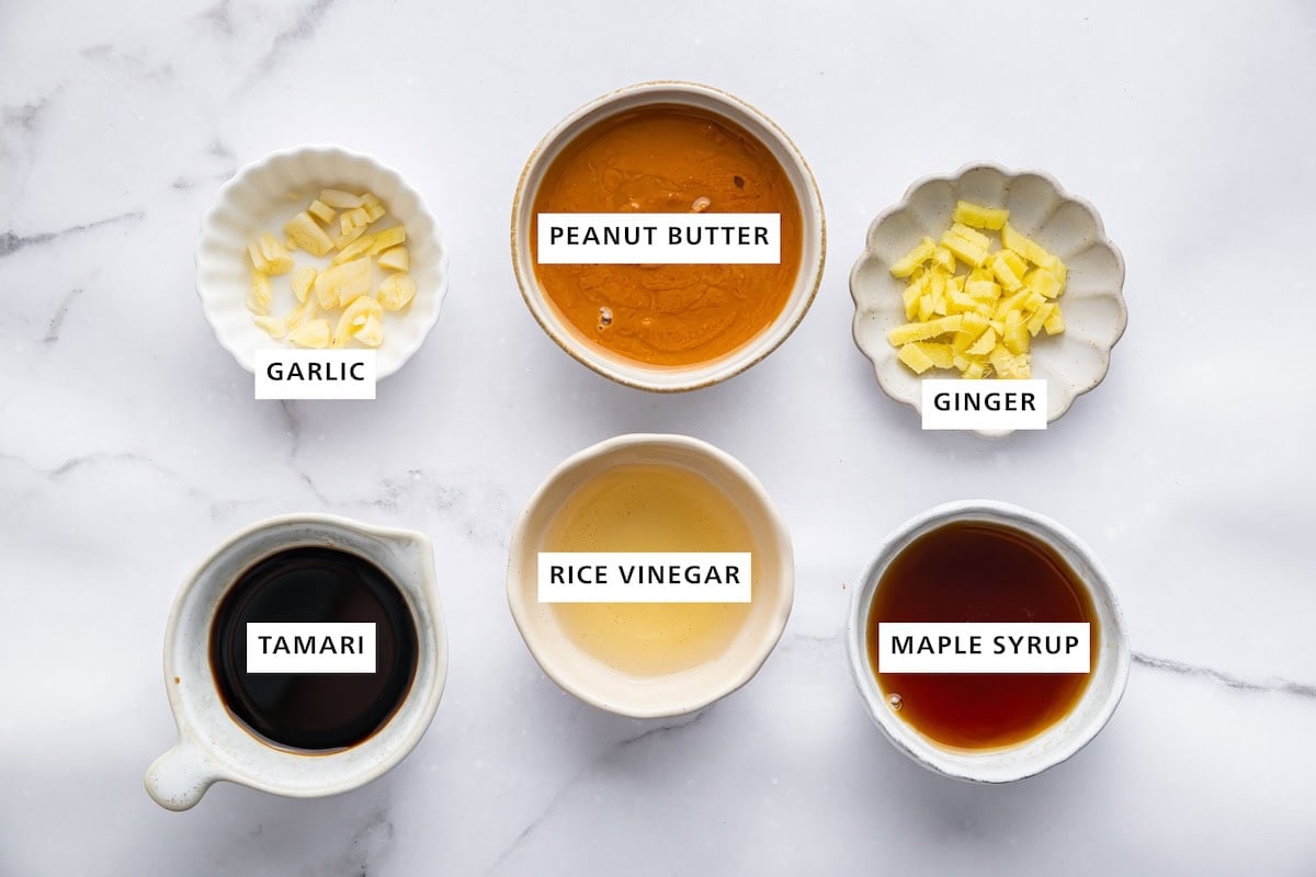 Ingredients measured out for peanut dressing: peanut butter, ginger, maple syrup, rice vinegar, tamari, and garlic.