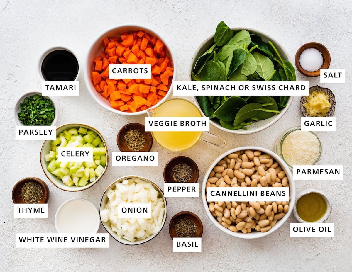 Ingredients measured out to make Mediterranean White Bean Soup: sea salt, garlic, parmesan, olive oil, cannellini beans, spinach, veggie broth, pepper, basil, carrots, oregano, onion, celery, white wine vinegar, tamari, parsley and thyme.
