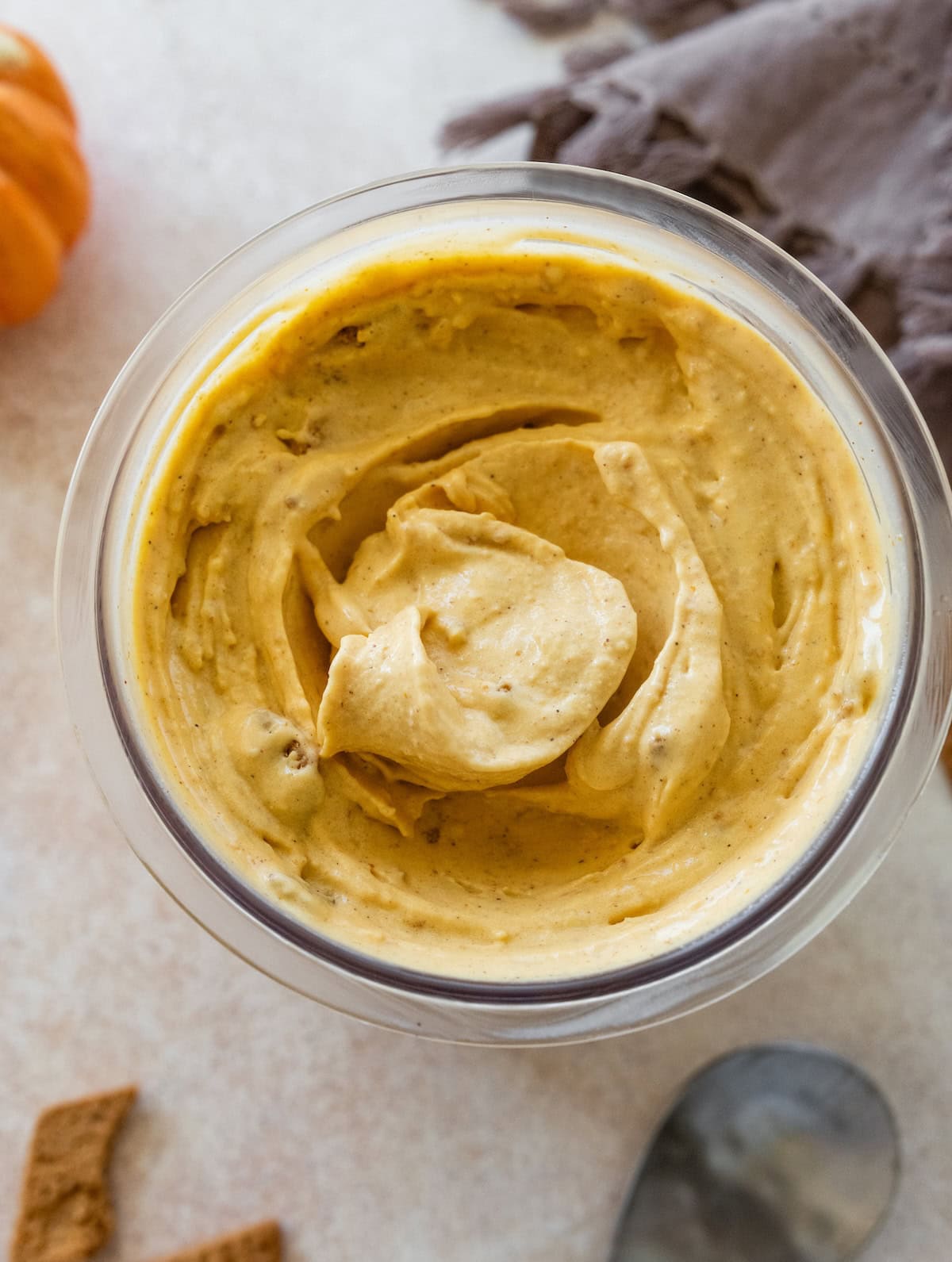 Cottage cheese pumpkin ice cream in a glass container with chunks of graham cracker mixed in.