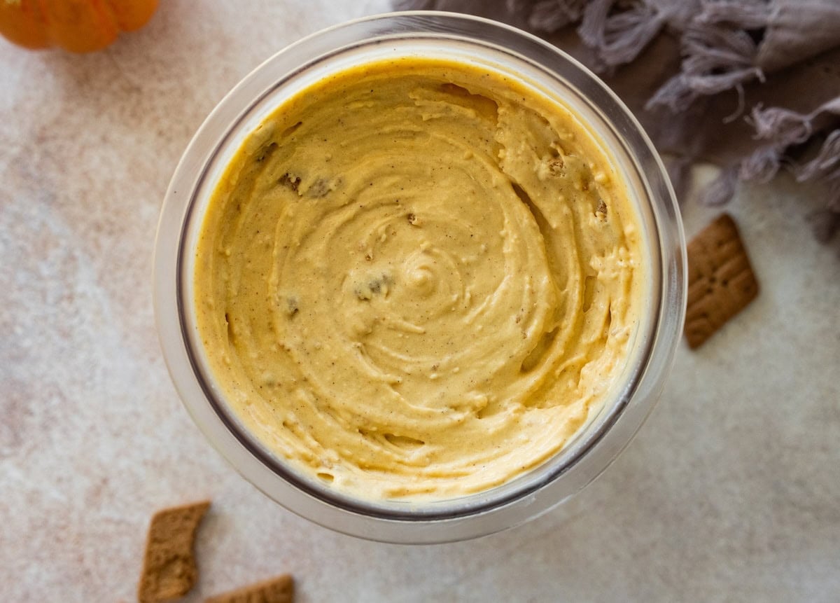 Frozen cottage cheese pumpkin ice cream in the Creami container with crushed graham crackers mixed in.