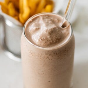A high protein copycat Wendy's frosty in a tall glass cup with a glass straw.