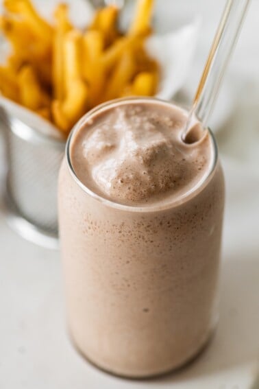 A high protein copycat Wendy's frosty in a tall glass cup with a glass straw.
