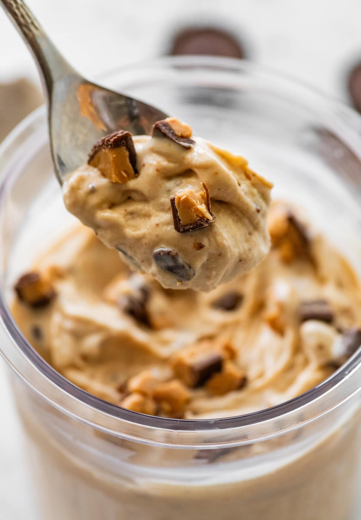 A spoonful of a peanut butter cup blizzard over a glass container of the blizzard.