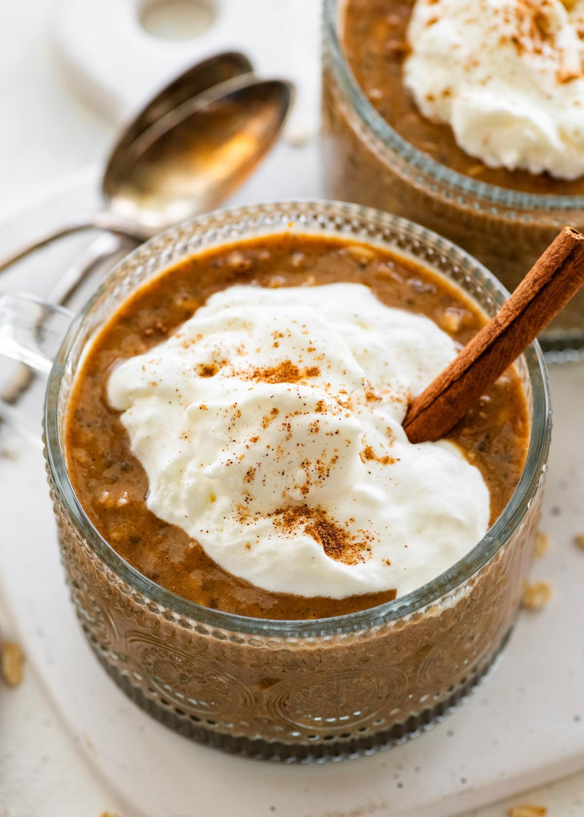 Pumpkin spice latte overnight oats in a glass topped with Greek yogurt and cinnamon.