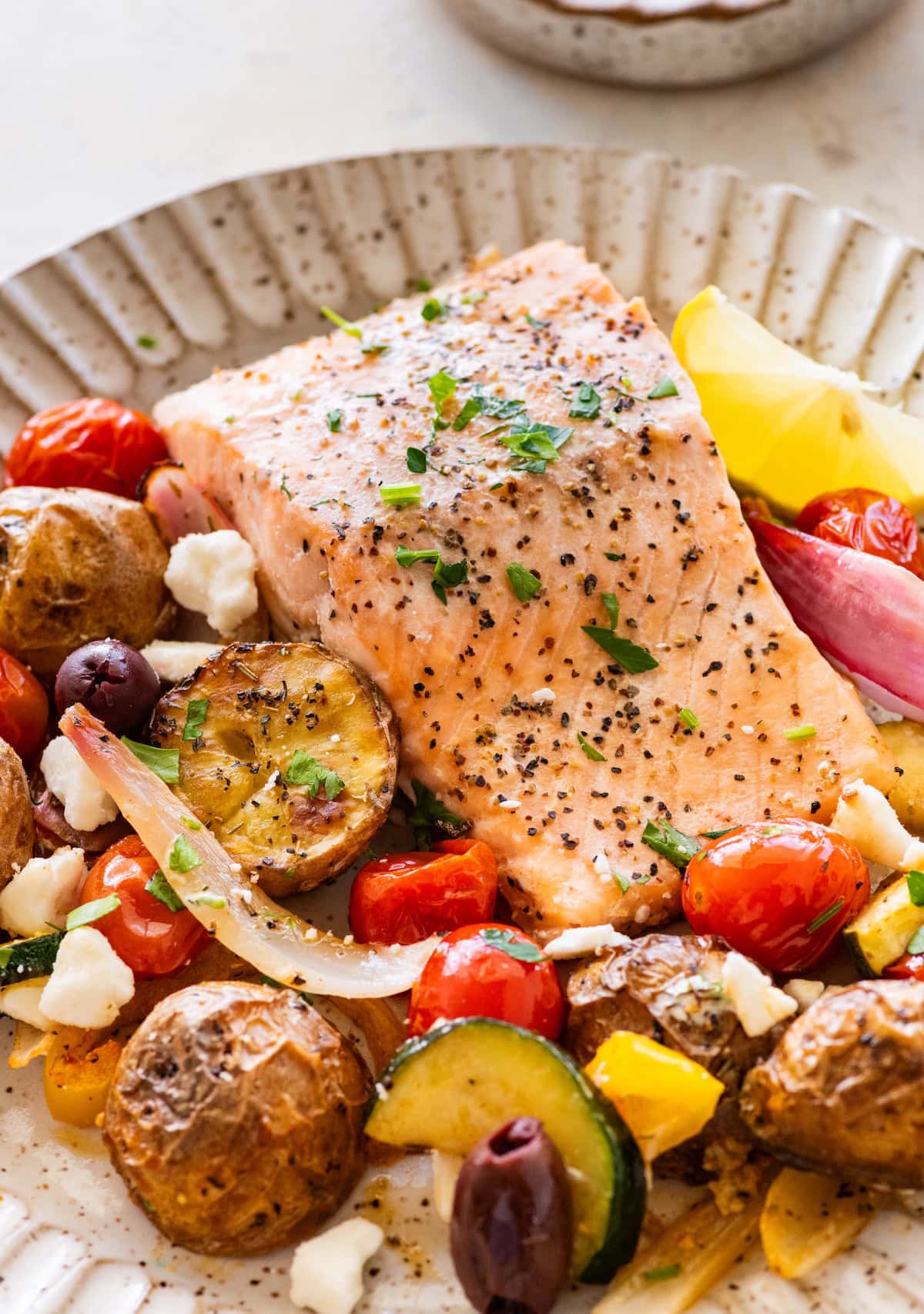 A serving of salmon, roasted potatoes, and veggies and a plate.