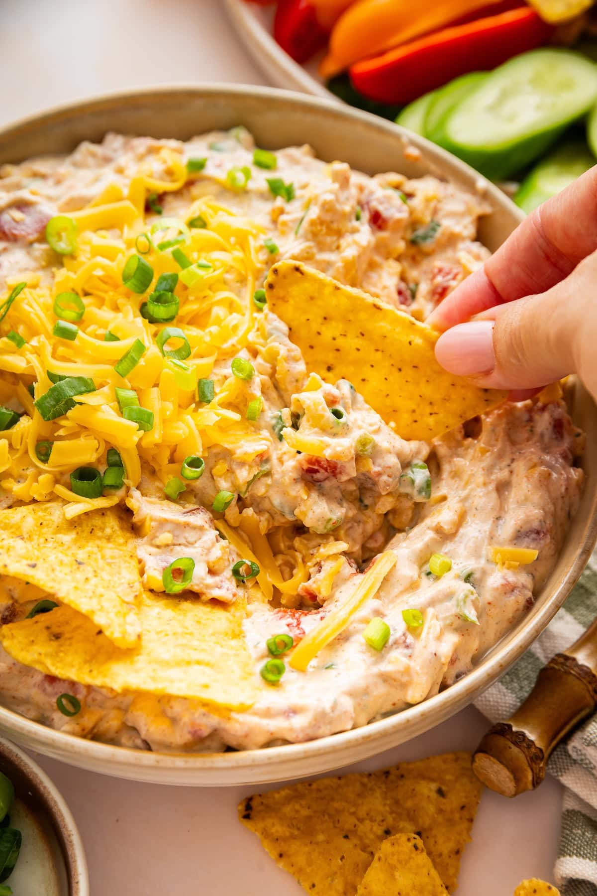 A hand dips a tortilla chip into a bowl of a cottage cheese boat dip.