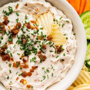 French onion dip served with chips topped with fresh chives and caramelized onions.
