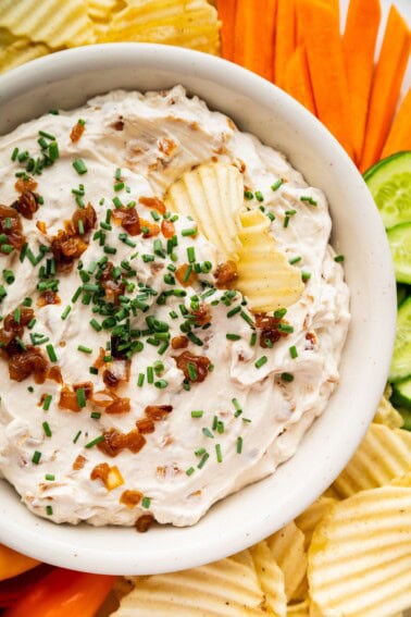 French onion dip served with chips topped with fresh chives and caramelized onions.