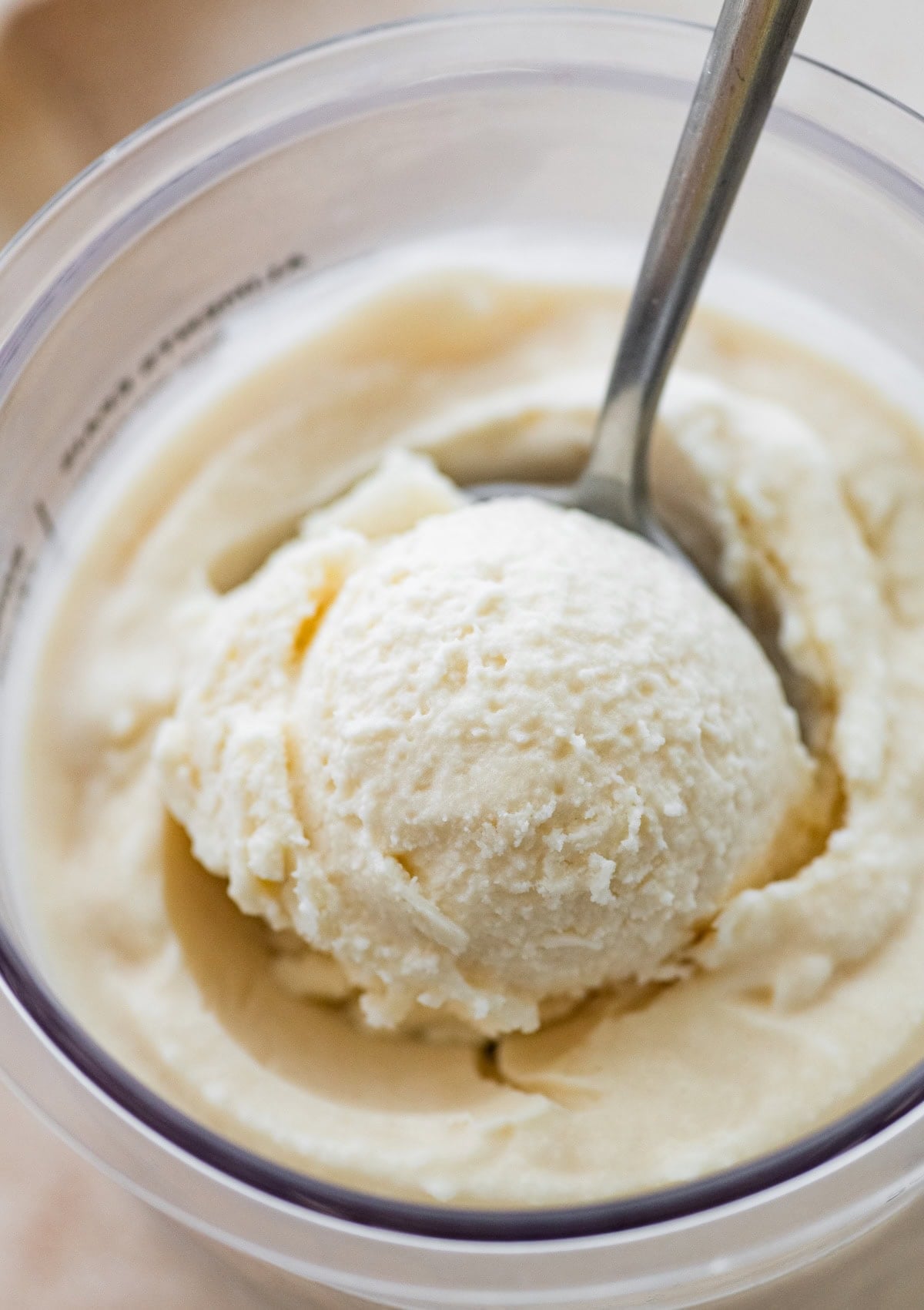 Greek yogurt ice cream being scooped from the Ninja Creami pint with a spoon.