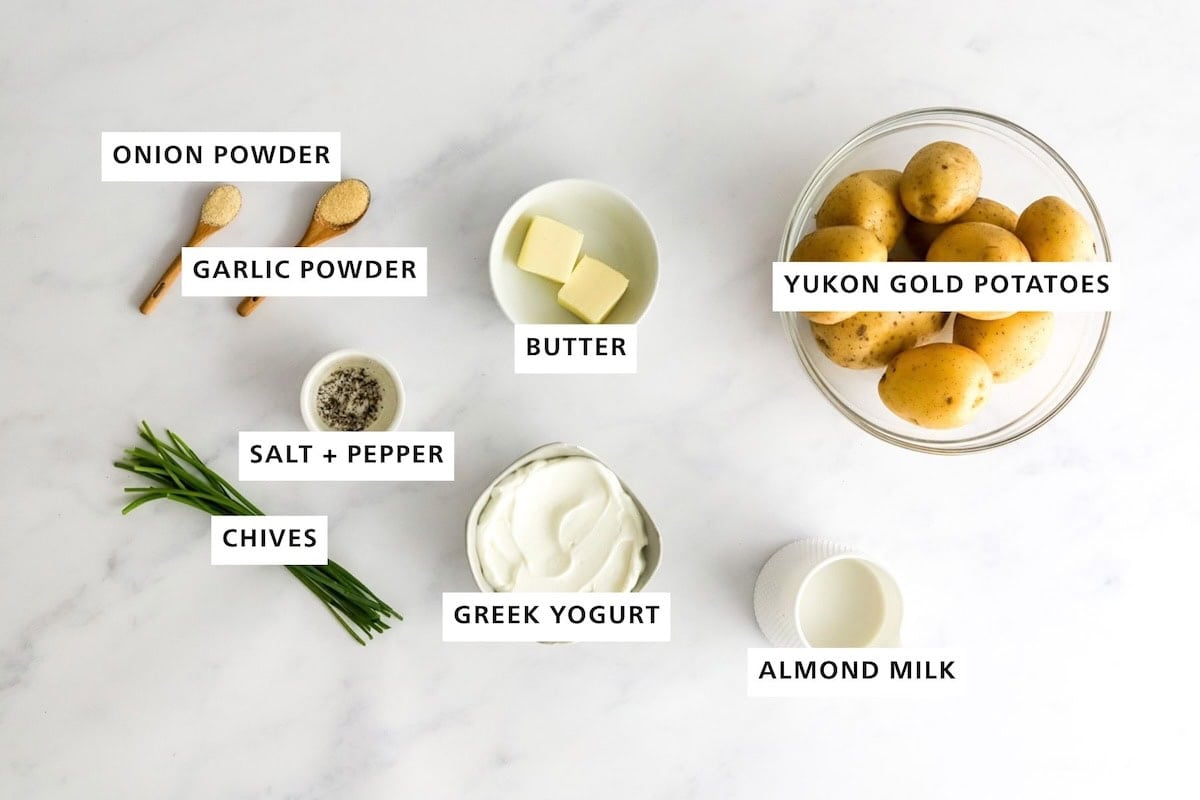 Ingredients measured out to make Healthy Mashed Potatoes: yukon gold potatoes almond milk, Greek yogurt, butter, salt, pepper, garlic powder, onion powder and chives.
