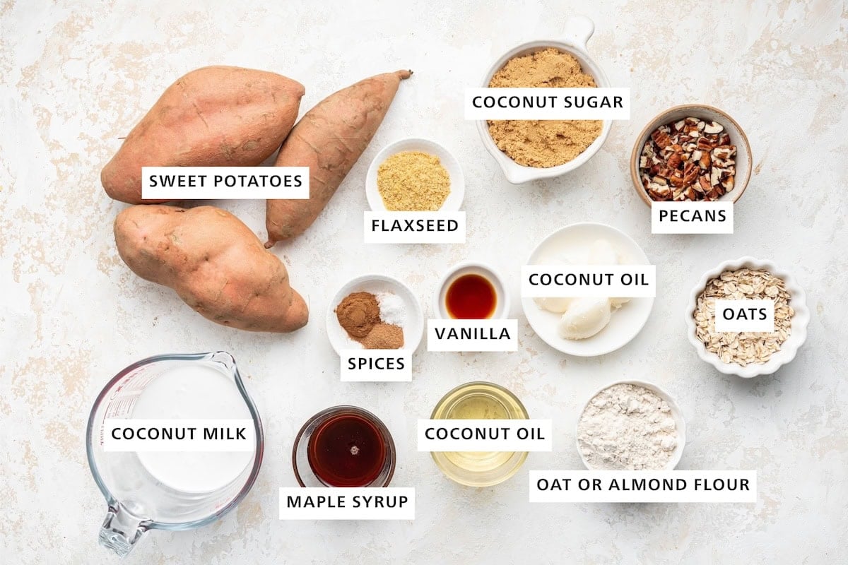 Ingredients measured out to make Healthy Sweet Potato Casserole: coconut milk, sweet potatoes, maple syrup, cinnamon, nutmeg, sea salt, ground flaxseed, coconut oil, vanilla, coconut sugar, oat flour, oats and pecans.