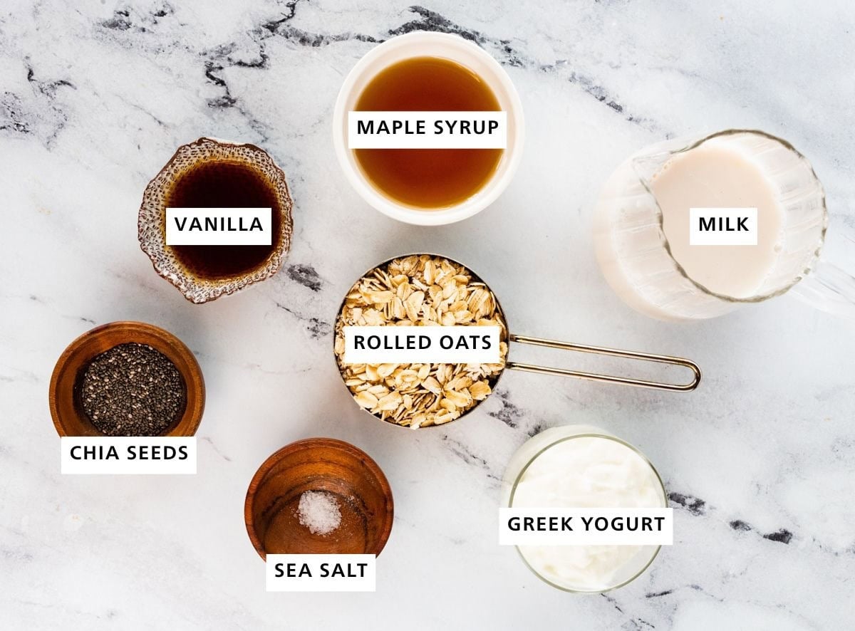 Ingredients measured out for overnight oats: rolled oats, sea salt, chia seeds, vanilla, maple syrup, greek yogurt, and milk.