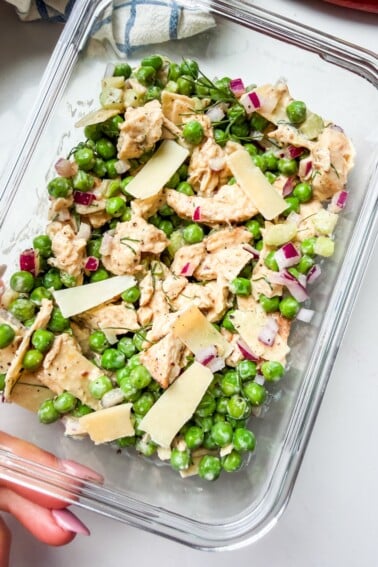 A glass container with peas, chicken and shaved parm (the viral chicken and peas salad).