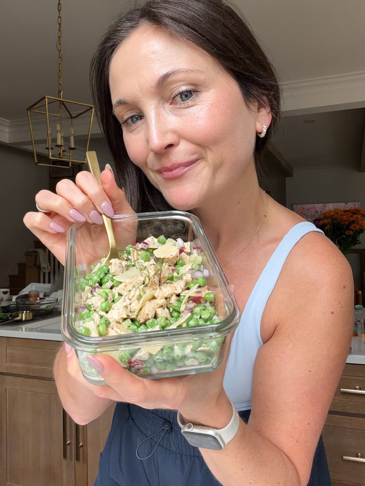 Brittany holding a glass container with the viral chicken and peas dish.