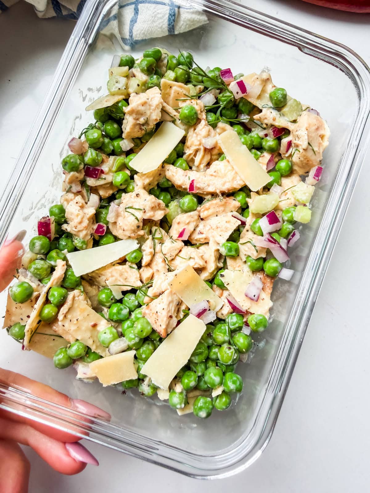A glass container with peas, chicken and shaved parm (the viral chicken and peas salad).