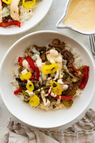 Philly cheesesteak bowl with ground beef, peppers, mushrooms, banana peppers and creamy cheese sauce over rice.