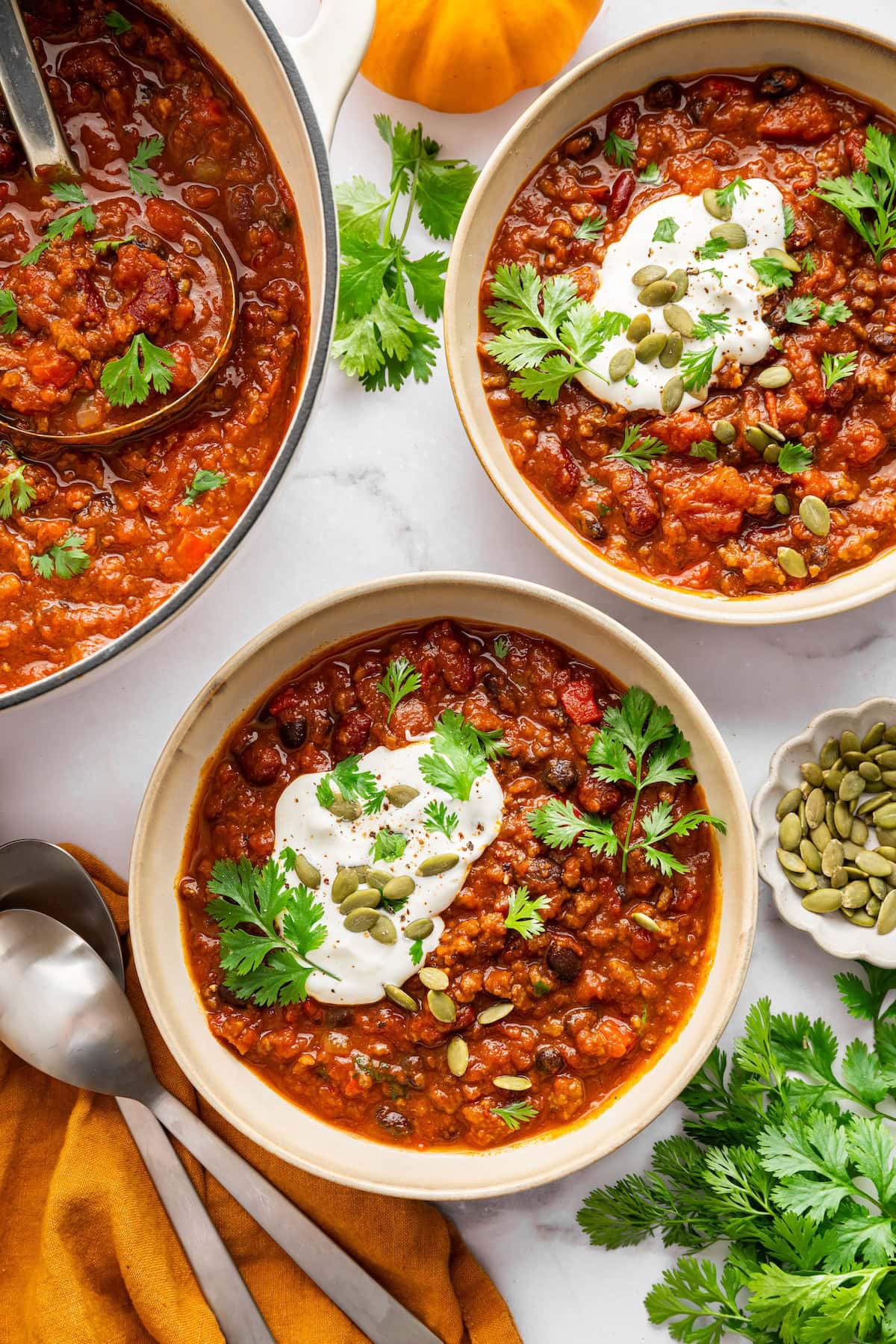 Bowls of pumpkin chili served with Greek yogurt, avocado, pepitas and fresh herbs.