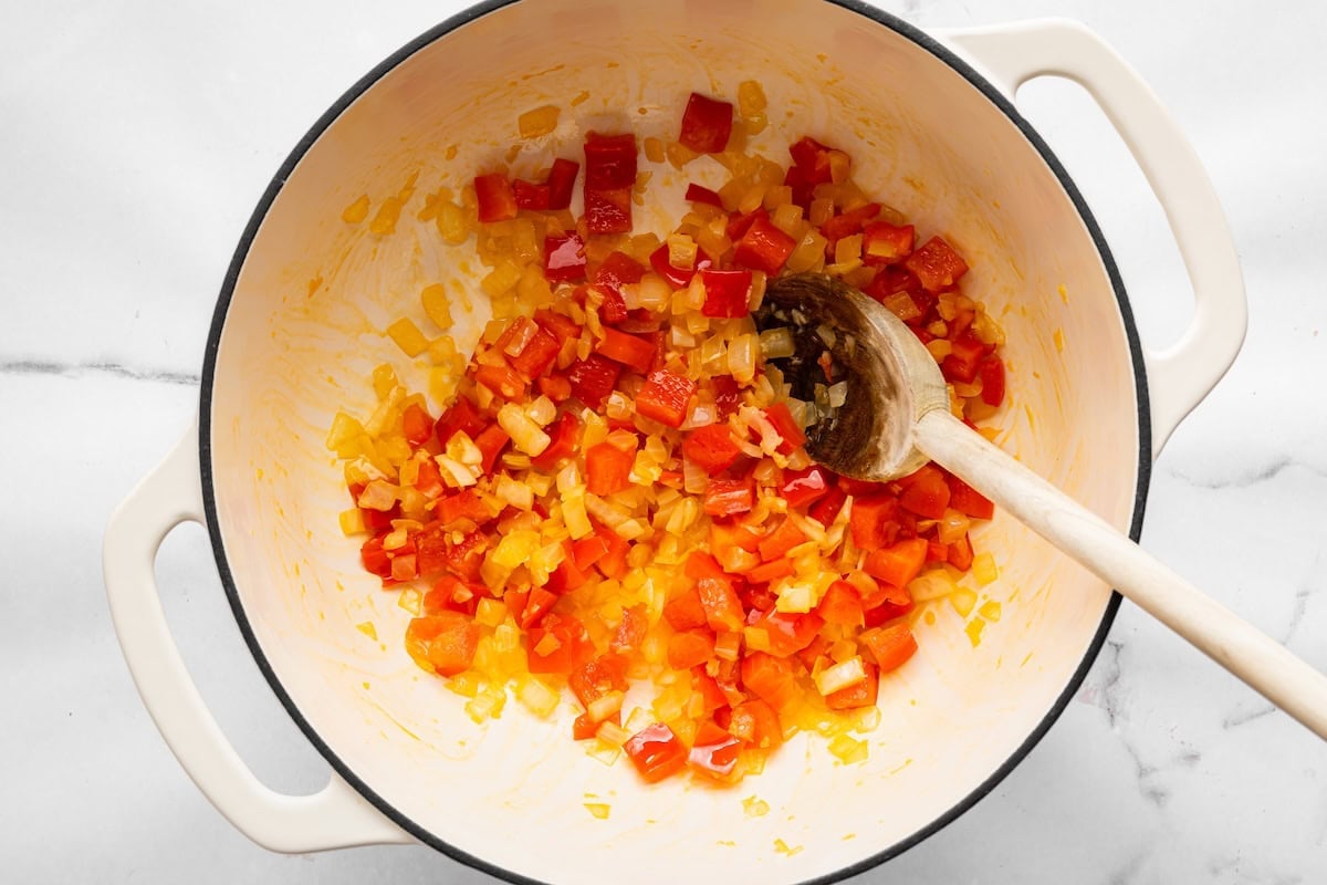 Diced onion, red bell pepper and garlic sautéing in a Dutch oven.