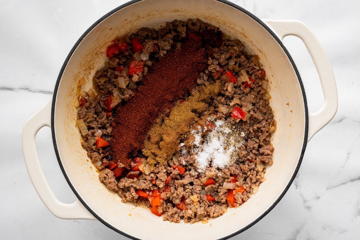Chili seasonings added to browned ground meat and vegetables.