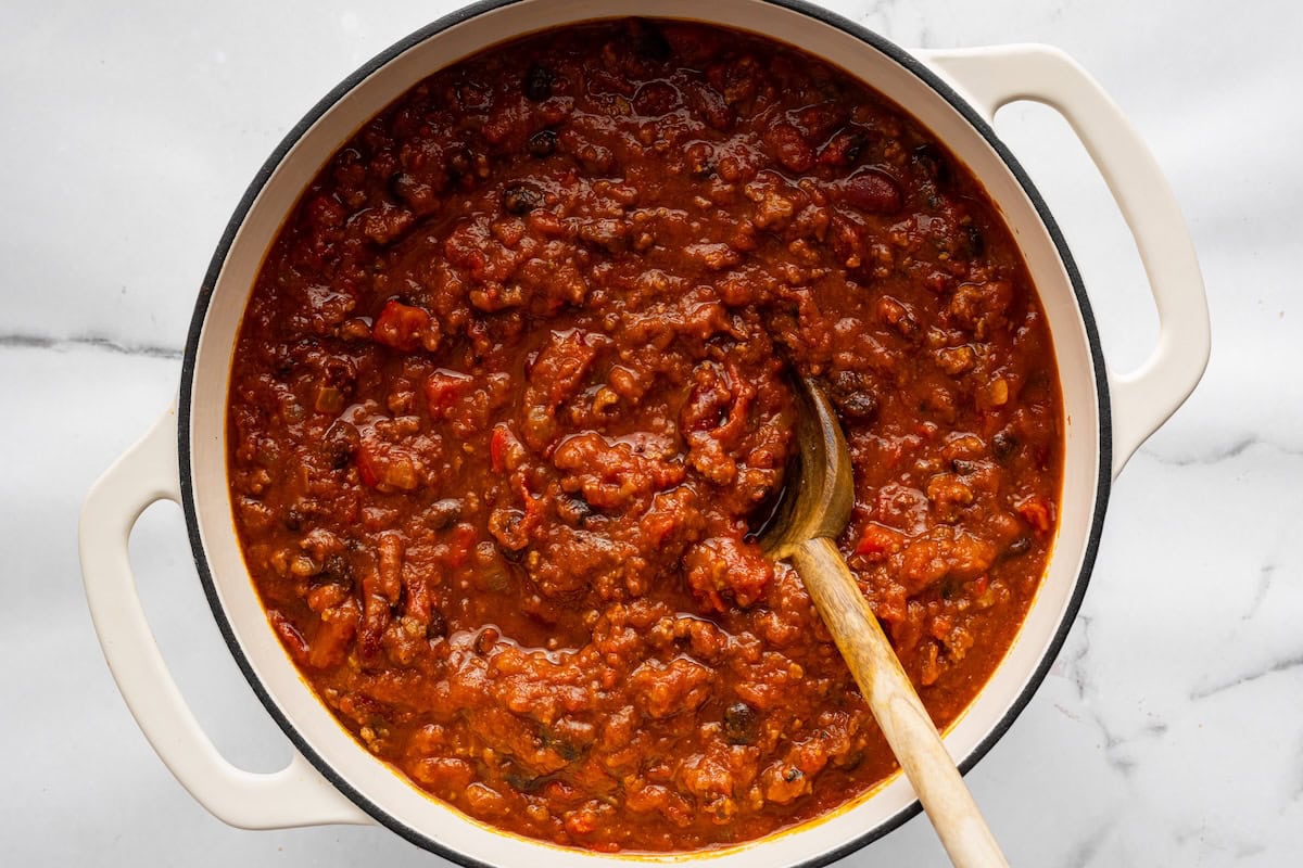 Thick pumpkin chili being stirred in a Dutch oven.