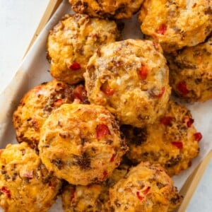 Close-up of baked breakfast biscuits with golden tops and visible red bell pepper and melted cheese.