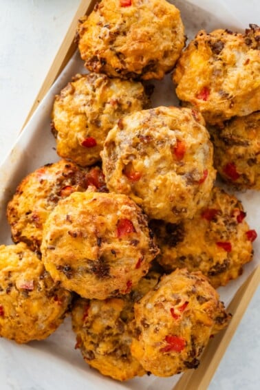 Close-up of baked breakfast biscuits with golden tops and visible red bell pepper and melted cheese.