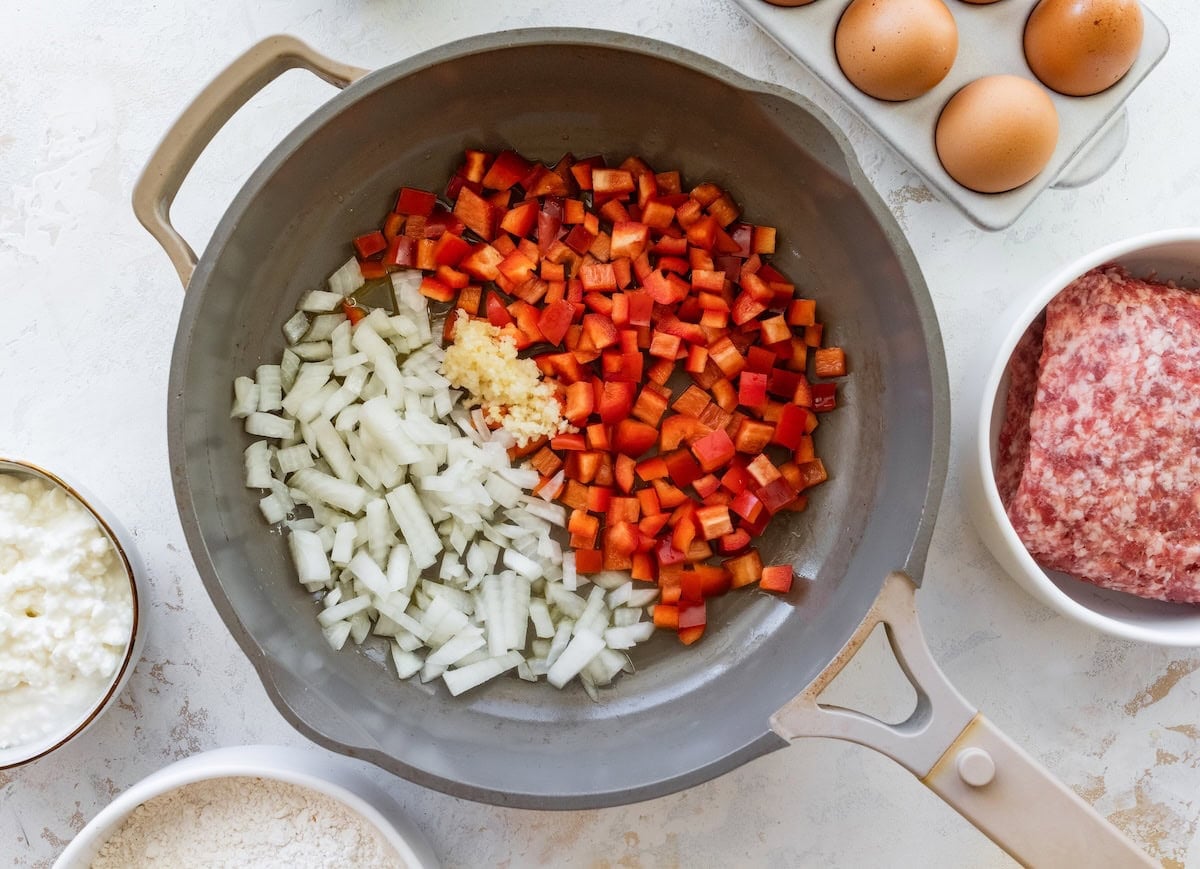 Diced onion, red bell pepper and garlic in a skillet before cooking.