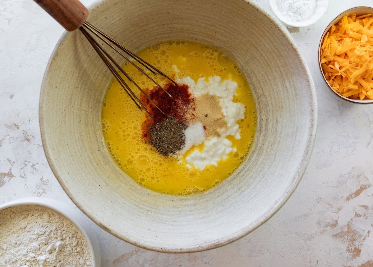 Whisked eggs with cottage cheese and seasonings in a mixing bowl.