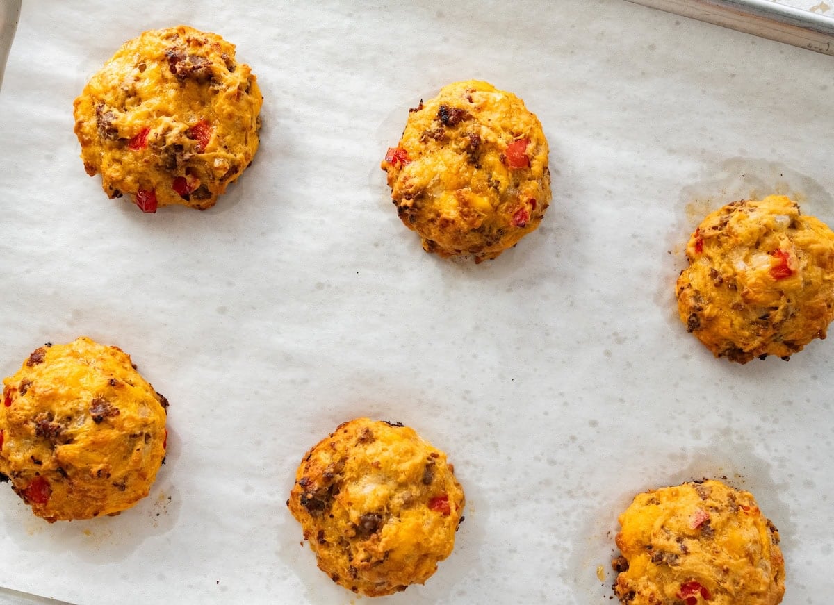 Cooked breakfast biscuits spaced apart on a parchment-lined baking sheet.