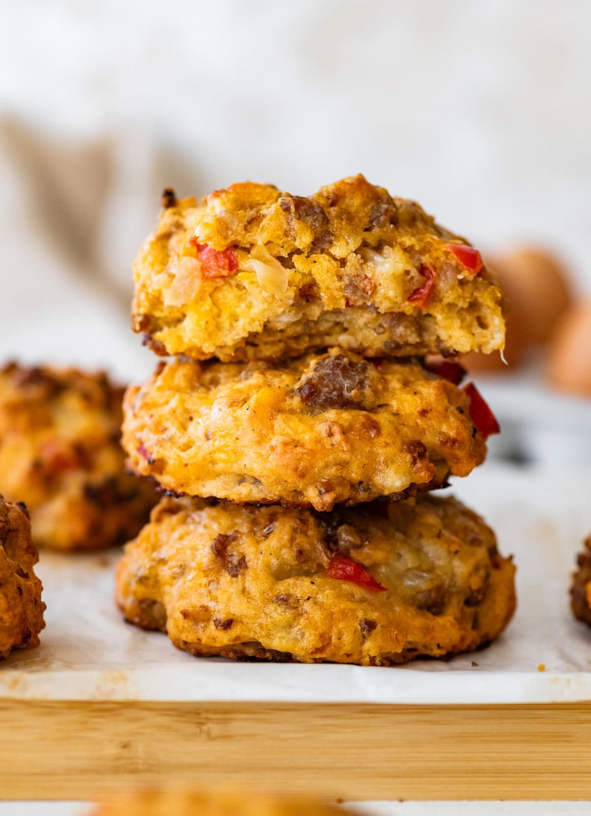 Two golden breakfast biscuits stacked on a plate, with the top biscuit split open to show the sausage, red bell pepper and cheese inside.