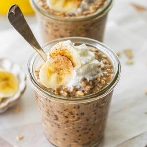 Two glass jars with banana bread latte overnight oats topped with greek yogurt and banana slices.