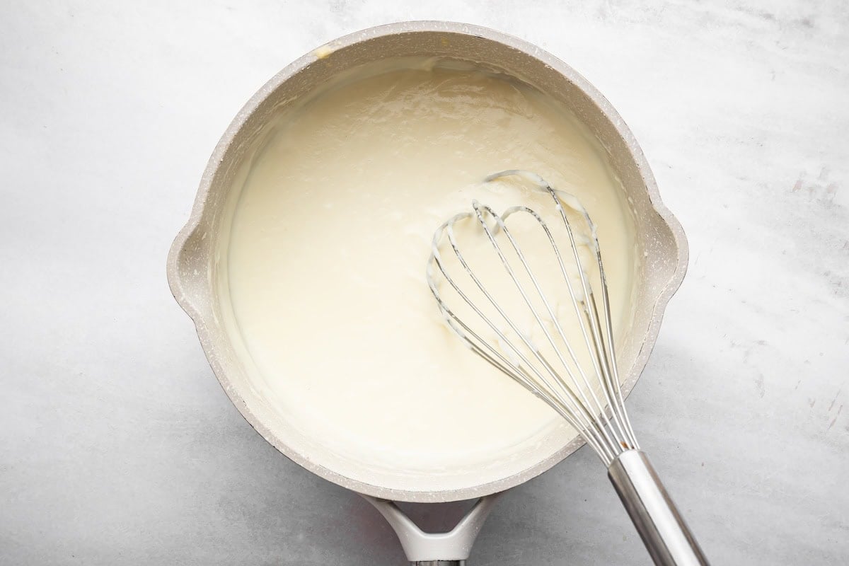 Milk sauce in a saucepan with a whisk, ready to stir into the chicken pot pie soup.