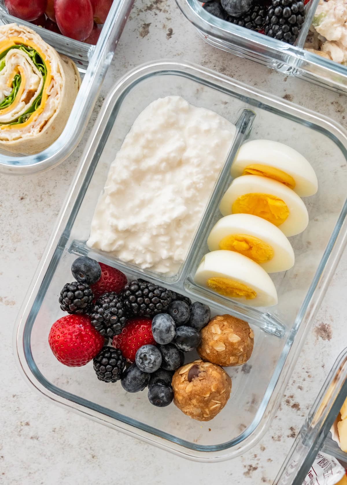 Cottage cheese protein box with sliced hard-boiled eggs, mixed berries and peanut butter protein balls.
