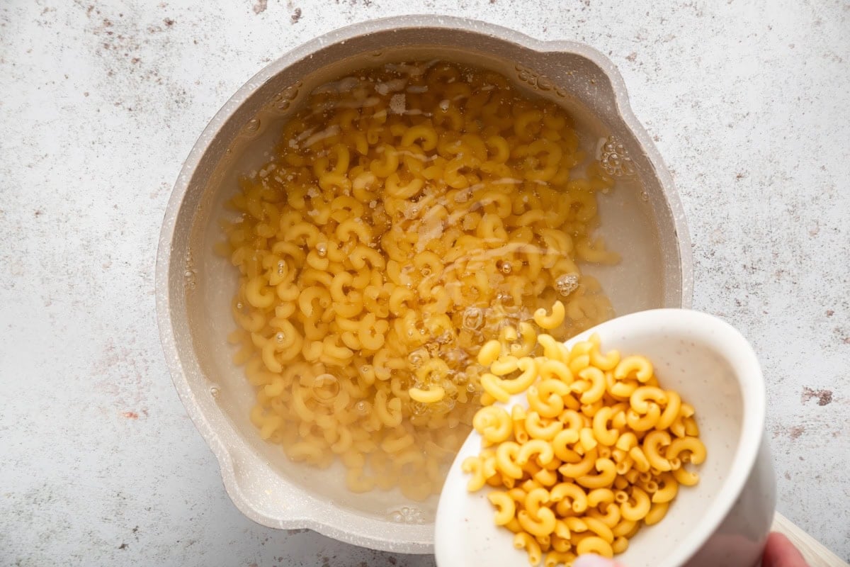 Elbow macaroni cooking in a pot of boiling water.