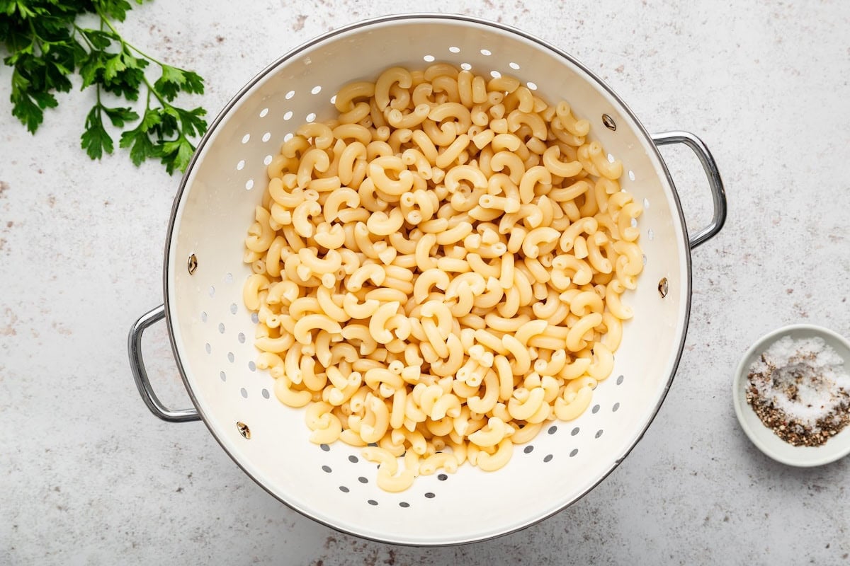 Cooked elbow macaroni draining in a colander.