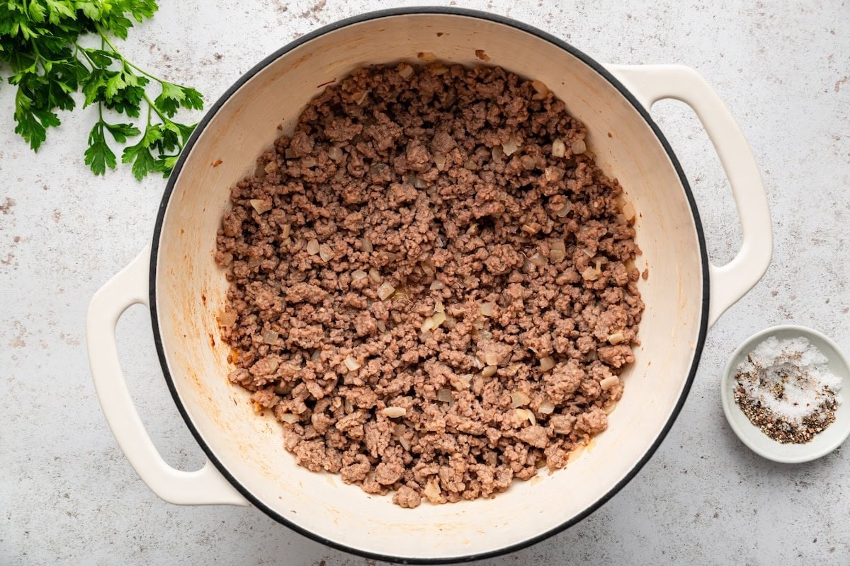 Browned ground beef crumbled in a Dutch oven.