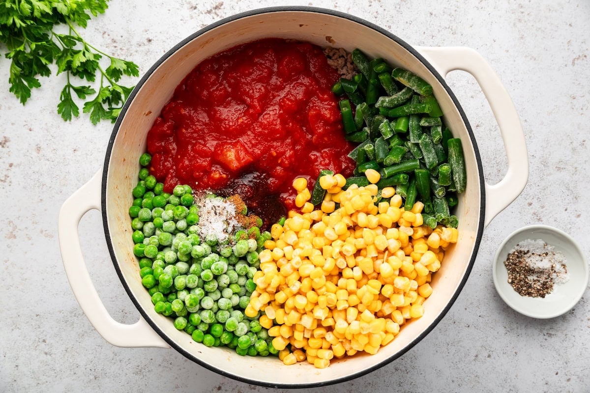Tomatoes, corn, peas, green beans and seasonings added to browned beef for goulash.