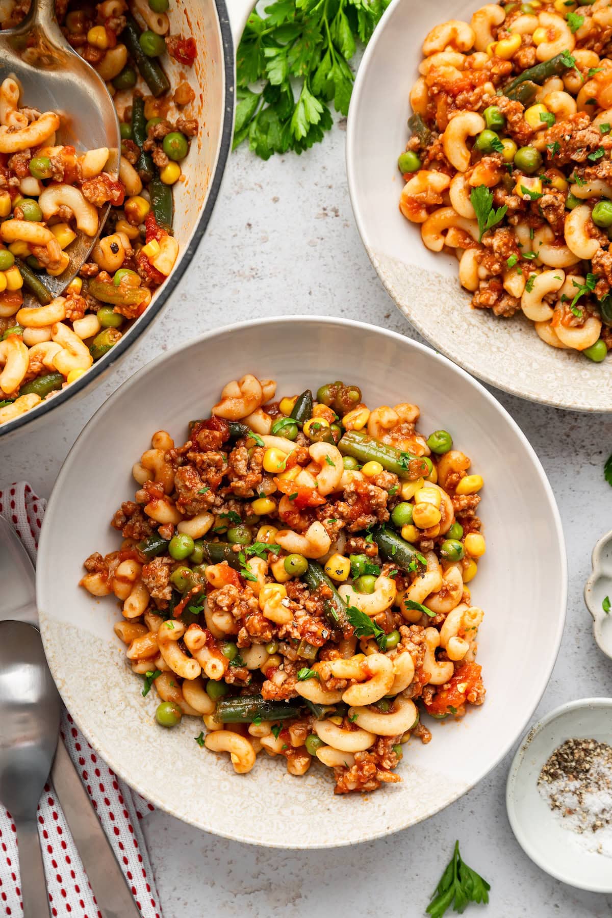 American goulash with beef, macaroni and vegetables served in white bowls.