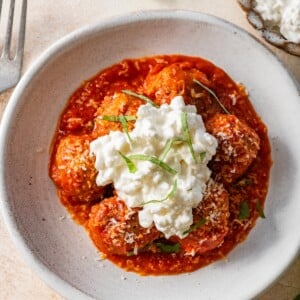Overhead view of Hailey Bieber meatballs with marinara, cottage cheese, Parmesan and basil in a bowl.