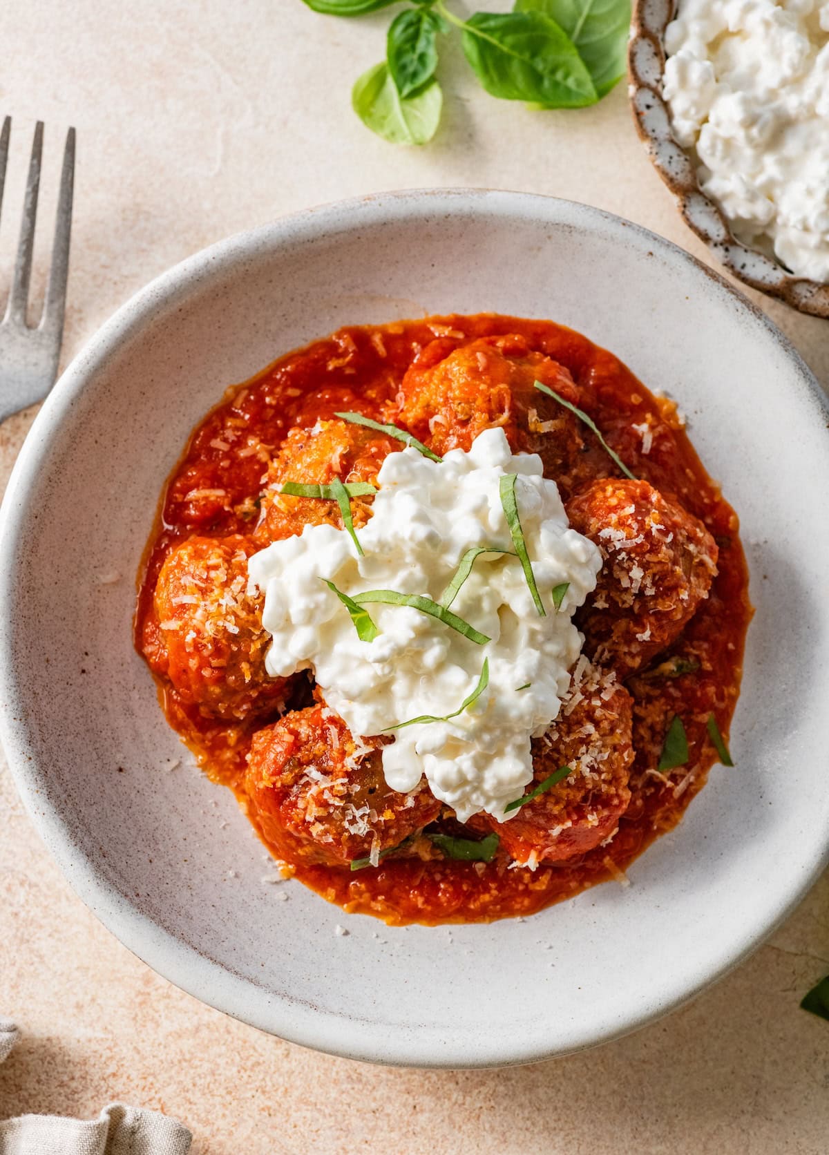 Overhead view of Hailey Bieber meatballs with marinara, cottage cheese, Parmesan and basil in a bowl.