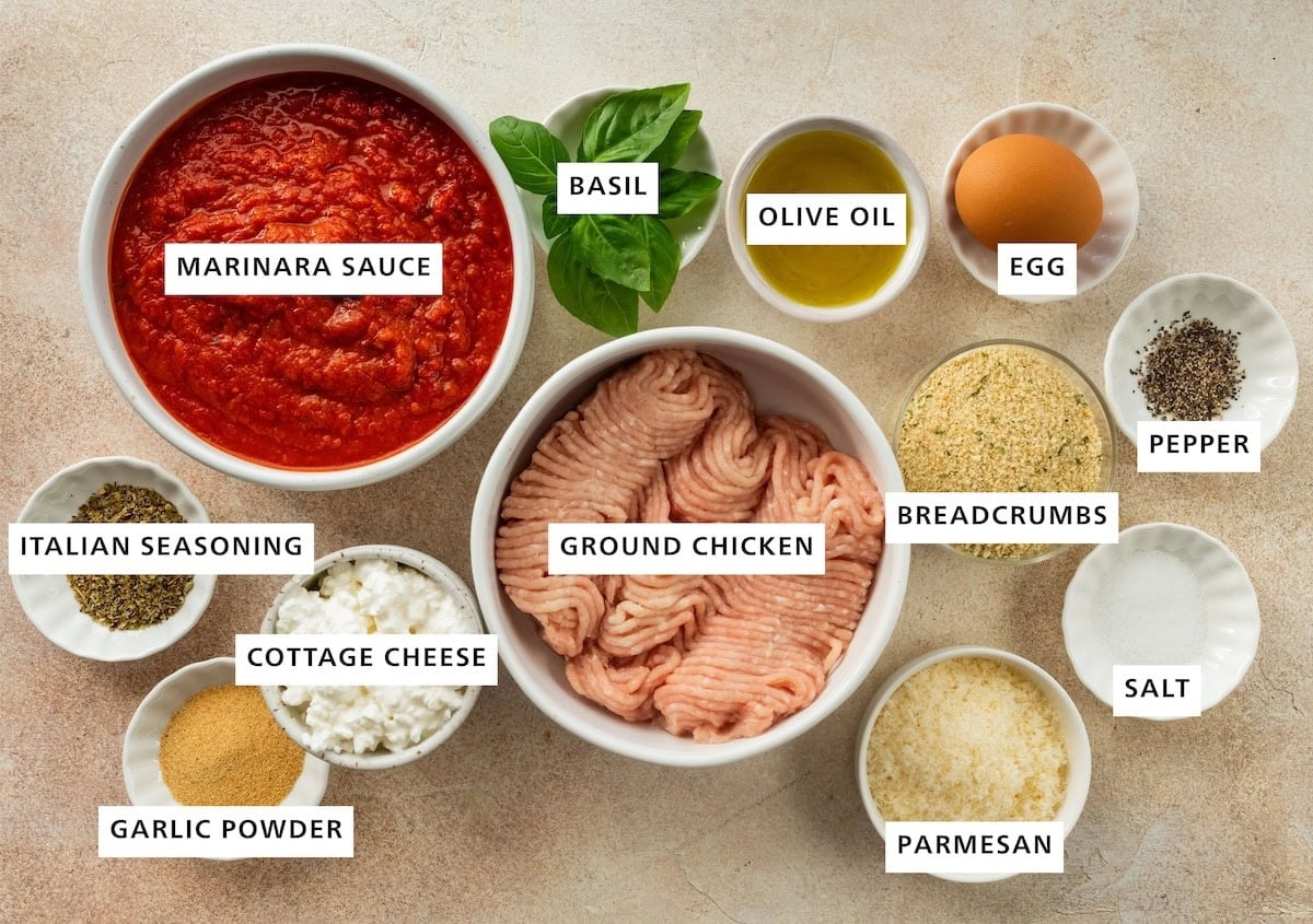 Ingredients measured out for a Hailey Bieber meatball recipe include: marinara sauce, basil, olive oil, an egg, breadcrumbs, pepper, salt, parmesan, ground chicken, cottage cheese, garlic powder, and Italian seasoning.